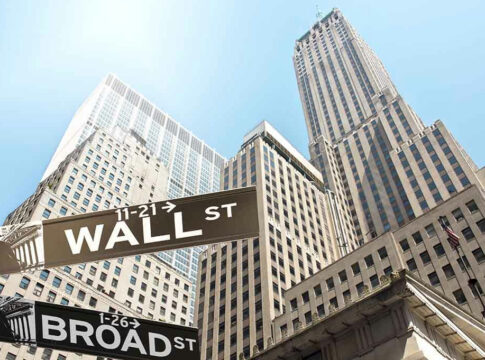 Wall Street and Broad Street signs, skyscrapers in background.