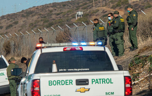 Border Patrol agents gather near trucks by a fence