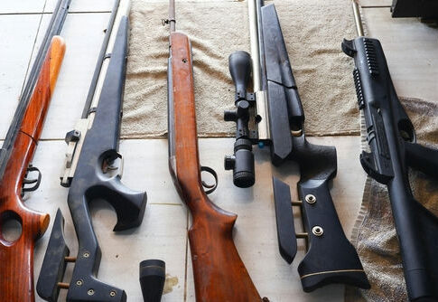 Assorted rifles and shotguns laid out on a table