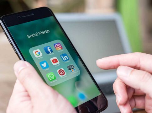 Person holding smartphone with social media app folder open